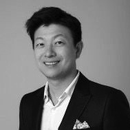 A trusted financial professional, wearing glasses and a suit, smiles at the camera in a black and white portrait.